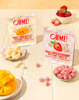 Two packages of OHME freeze-dried fruit snacks on a tiled surface with fruit and bowls.