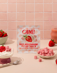 OHME! freeze-dried strawberry yogurt crunch packaging with strawberries and yogurt on a pink tiled background