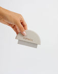 A hand holding a white pet grooming comb with the brand 'PUPWELL' inscribed on it against a white background.