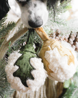 Dog playing with a plush toy shaped like a duck among Christmas tree decorations