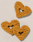 Three heart-shaped dog treats on a beige background
