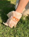 Person holding a bag labeled 'POO' with text on grass
