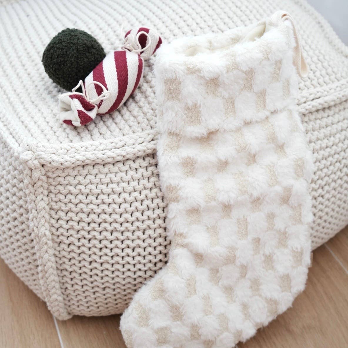 Knitted basket with a plush toy and white blanket on a wooden floor