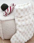 Knitted basket with a plush toy and white blanket on a wooden floor