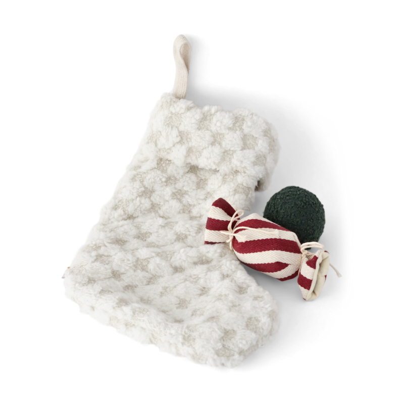 White textured stocking with a red and white candy and green ornament on a white background