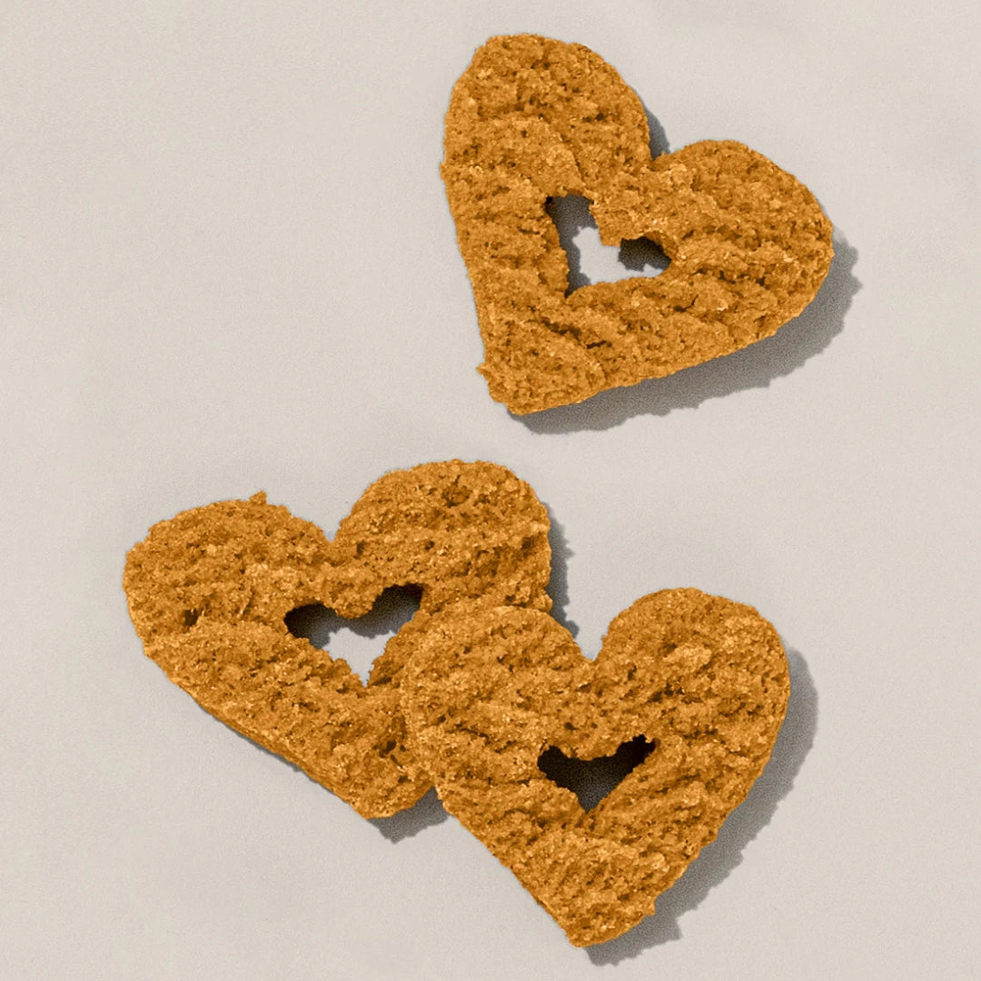 Three heart-shaped dog treats on a beige background